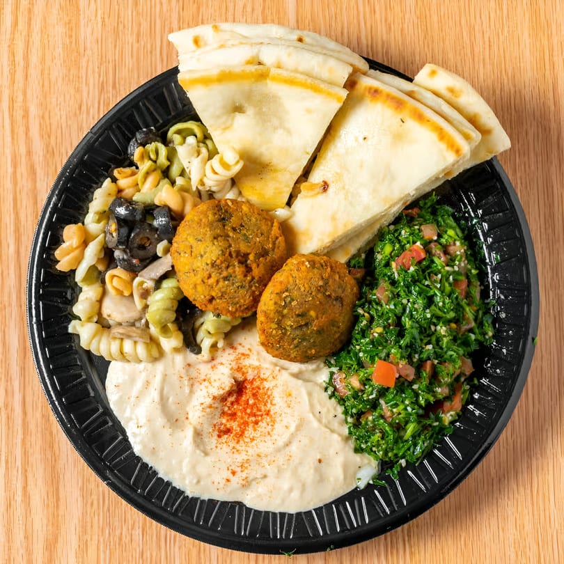Taza Grill Mediterranean platter with falafel, hummus, tabbouleh, pasta salad, and pita bread.