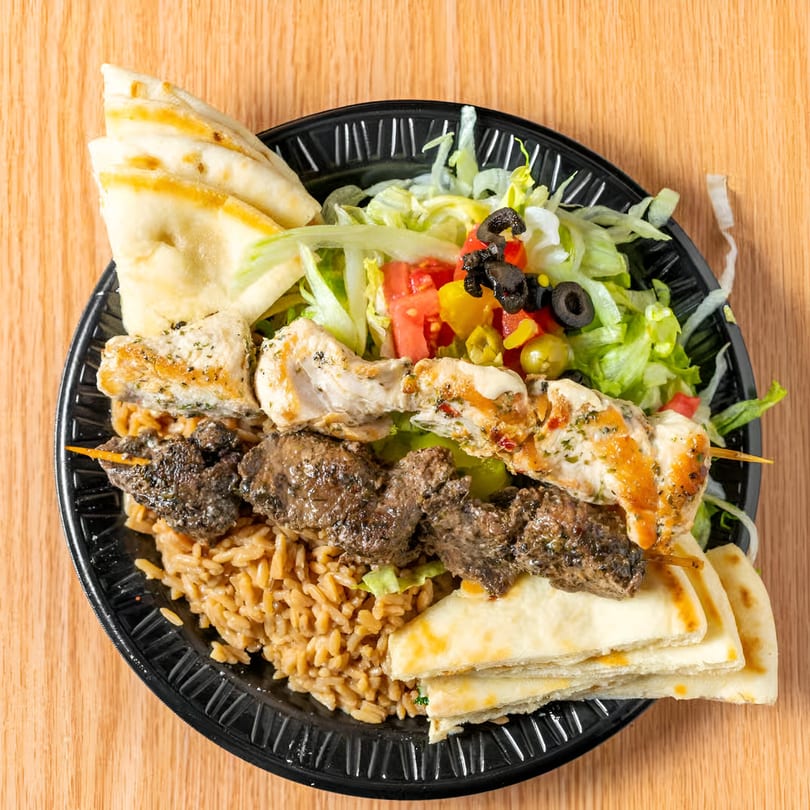 Taza Grill's Mediterranean platter with chicken and beef kebabs, rice, salad, and pita bread.